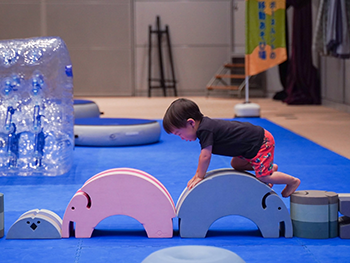 室内遊び場で、ゾウの形をしたブロック遊具(ボブルス)を登って遊ぶ小さな子どもの写真